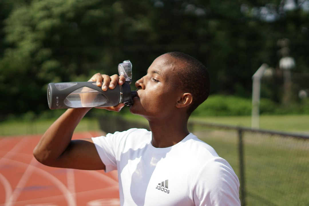 Sportif buvant dans une gourde réutilisable pendant une activité en extérieur